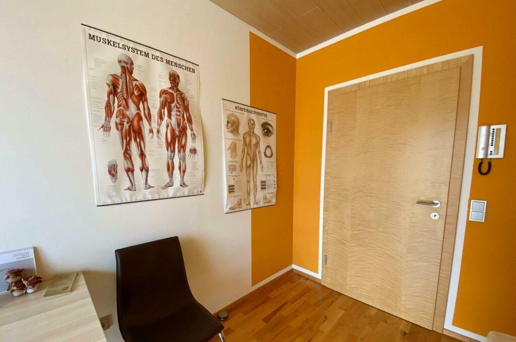 Eingangsbereich der Tuina Praxis Karrer mit Anatomie Bilder an der Wand